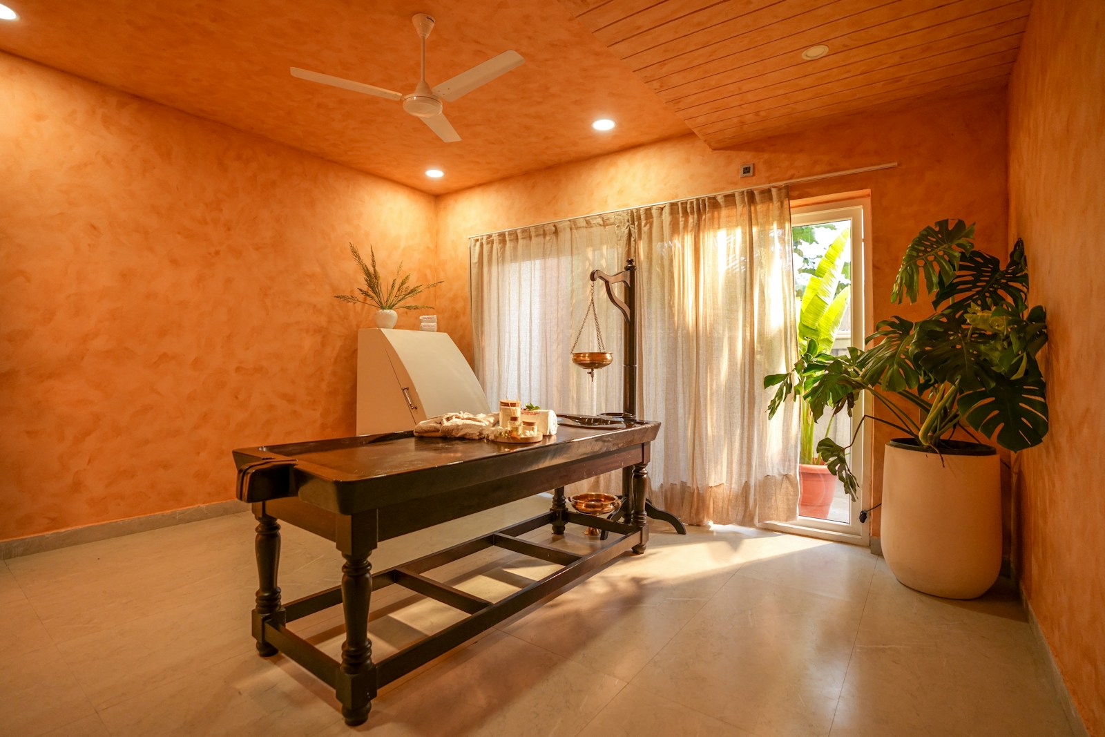 Warm massage treatment room with plants and treatment table